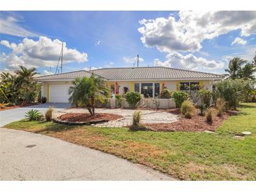 Charming single-story home with a tile roof, well-manicured lawn and circular driveway surrounded by tropical landscaping at 2807 Coral Way, Punta Gorda, FL 33950