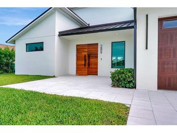 Contemporary home featuring a light-colored exterior and modern wood double-door entry at 289 Long Meadow Ln, Rotonda West, FL 33947
