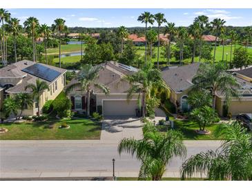 Beautifully landscaped home boasts lush greenery, swaying palms, and a serene lake view, offering a tranquil Florida lifestyle at 305 Siena Vista Pl, Sun City Center, FL 33573