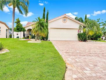 Charming single-story home features lush landscaping, a brick driveway, and a two-car garage under a bright blue sky at 4907 Kilty E Ct, Bradenton, FL 34203
