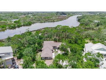 Stunning aerial view of home surrounded by lush greenery and waterfront views at 5935 River Forest Cir, Bradenton, FL 34203