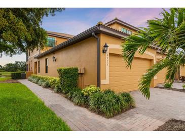 Inviting home exterior featuring a two-car garage, lush landscaping, and a charming brick walkway at 6923 Grand Estuary Trl # 101, Bradenton, FL 34212