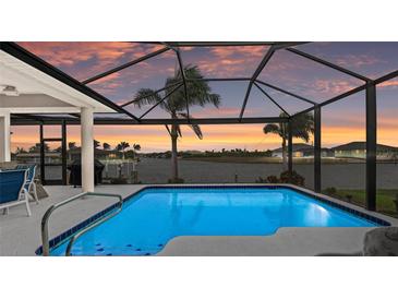 Sparkling pool with a screened enclosure offers a beautiful waterfront view during sunset at 8106 Arlewood Cir, Port Charlotte, FL 33981