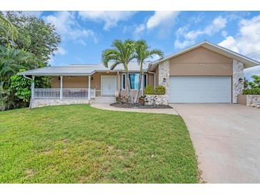 Charming single-story home features a lush lawn, two-car garage, and covered front porch with stone accents at 1461 Marlin St, Nokomis, FL 34275