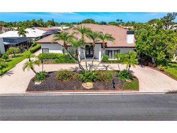 Elegant home featuring a red tile roof, lush landscaping, and a brick-paved driveway, offering curb appeal at 1484 Seafarer Dr, Osprey, FL 34229