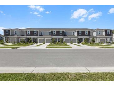 Street view of newly built townhomes with manicured lawns and sidewalks on a sunny day at 16652 Bergamo Pl, Bradenton, FL 34211