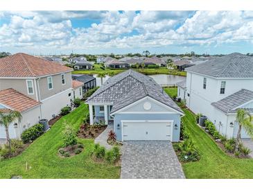 Beautiful single Gathering home featuring a gray tile roof, paver driveway, and a well maintained lawn with landscaped accents at 2565 Star Apple Way, Sarasota, FL 34240