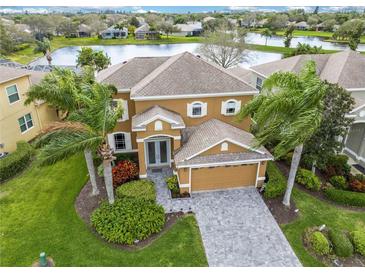 Beautiful home with a tile roof, well-maintained landscaping, and a paver driveway with a lake view in the background at 3671 Summerwind Cir, Bradenton, FL 34209