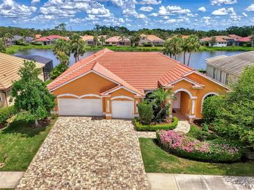 Beautiful orange home with a red tile roof, lush landscaping, and a paver driveway at 4957 Sabal Lake Cir, Sarasota, FL 34238