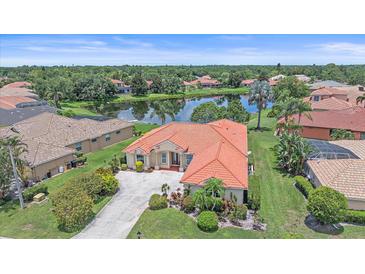 Beautiful lake view home with a red tile roof and mature landscaping in a desirable neighborhood at 5523 Secluded Oaks Way, Sarasota, FL 34233