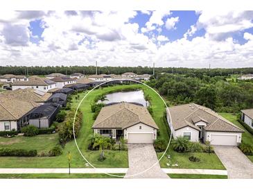 An aerial view of a charming home with a pond view, lush lawn, and brick paved driveway at 6507 Clairborne Ln, Bradenton, FL 34211