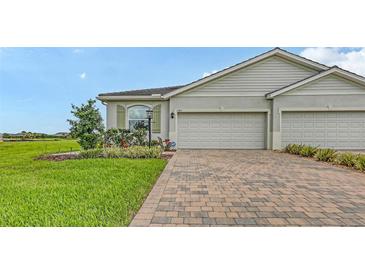 Charming home with a two-car garage, brick driveway, and lush green lawn, perfect for a Gathering at 17817 Pastureland Ave, Lakewood Ranch, FL 34211