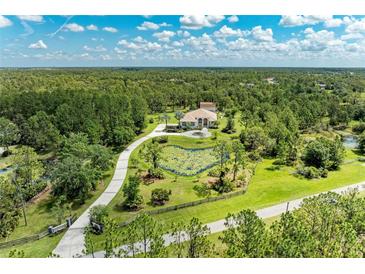 Stunning aerial view of a luxury home with a long driveway and serene pond at 20207 71St E Ave, Bradenton, FL 34211