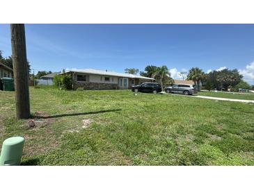 Charming single-story home with a well-maintained lawn and a stone facade and driveway at 23067 Elmira Blvd, Punta Gorda, FL 33980