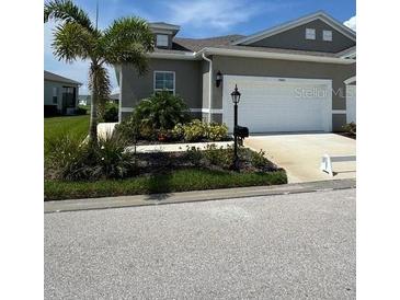 A well-maintained, one-story home with a two-car garage and a manicured lawn, under a partly cloudy sky at 24803 Buckingham Way, Port Charlotte, FL 33980