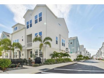 Charming two-story townhome features a white exterior, balcony, and a fenced-in patio with lush landscaping at 2500 Boone Ct, Sarasota, FL 34237