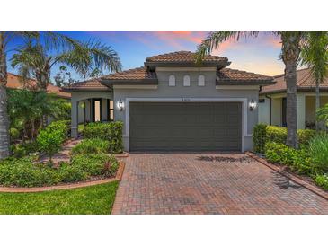 Charming home featuring a brick driveway, a two-car garage, manicured landscaping, and a tile roof at 2525 Daisy Dr, North Port, FL 34289