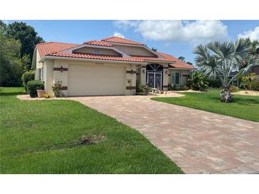 Charming home featuring a red tile roof, attached garage, well-manicured lawn, and a brick driveway at 25433 Colon Dr, Punta Gorda, FL 33983