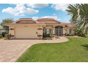 Charming single-story home features a red tile roof, lush landscaping, and a brick paver walkway and driveway at 25433 Colon Dr, Punta Gorda, FL 33983