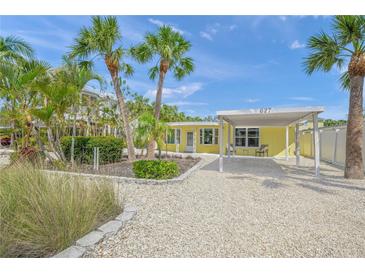 Charming yellow home featuring tropical landscaping, a covered carport, and a white shell driveway at 627 Avenida Del Norte, Sarasota, FL 34242