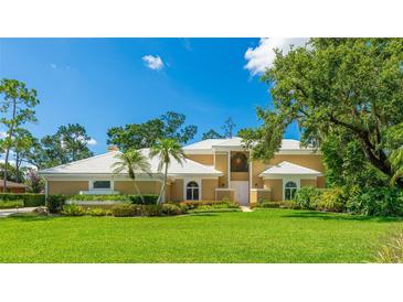 Stunning home featuring a well-manicured lawn and tropical landscaping, creating an inviting curb appeal at 7404 Weeping Willow Blvd, Sarasota, FL 34241