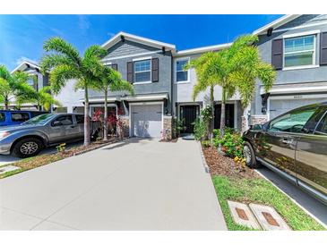 Charming townhome with a well-manicured lawn, lush landscaping, and a driveway with two cars at 8676 Ice Wine St, Sarasota, FL 34238
