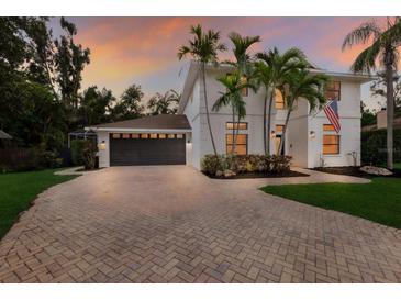 Elegant two-story home with lush landscaping, brick driveway, and a striking white facade at 9122 16Th Avenue Nw Cir, Bradenton, FL 34209