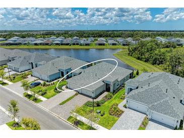 Stunning aerial view of home overlooking tranquil pond with manicured landscaping and charming blue-grey exterior at 11685 Great Brook Ln, Parrish, FL 34219