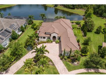 An aerial view of an estate home with a tile roof, circular drive, and a private lake view at 16531 Kendleshire Ter, Lakewood Ranch, FL 34202