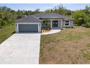 Charming one-story home featuring a large driveway, a two-car garage, and a well-maintained yard at 19185 Sherbrooke Ave, Port Charlotte, FL 33954