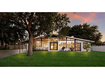 Charming exterior with floor-to-ceiling windows and a well-manicured lawn at sunset at 4232 Pandora Rd, Venice, FL 34293