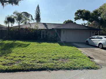 Charming single-story home with lush green lawn and mature trees under a bright sky at 4343 Arrow Ave, Sarasota, FL 34232