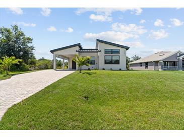 Striking modern home with lush lawn, covered parking, and charming front yard landscaping at 5339 Gulfport Ter, Port Charlotte, FL 33981