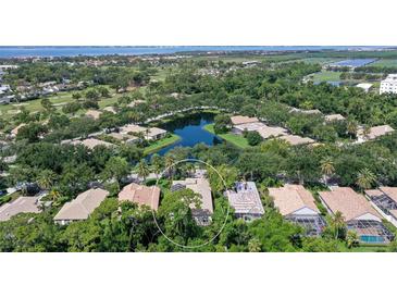An aerial view of a home situated on a verdant lot, surrounded by a pond, lush trees, and a golf course in the distance at 5839 Los Verdes Ct, Bradenton, FL 34210