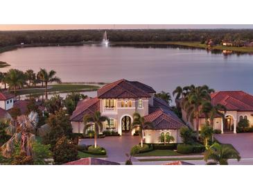 Stunning waterfront home with a tile roof, lush landscaping, and a brick driveway at 7665 Haddington Cv, Bradenton, FL 34202