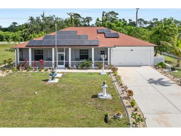 Charming single-story home featuring a red roof, solar panels, well-manicured lawn and a long driveway at 25324 Alicante Dr, Punta Gorda, FL 33955