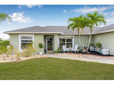 Charming single-story home with a well-manicured lawn, landscaping, and quaint front patio seating at 6178 Coliseum Blvd, Port Charlotte, FL 33981
