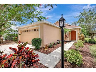 Charming one-story home featuring a manicured front yard with colorful landscaping and a cozy, inviting entrance at 6352 Robin Cv, Lakewood Ranch, FL 34202