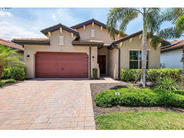 Charming single-Gathering home featuring a red brick driveway, two-car garage, and lush tropical landscaping at 201 Vinadio Blvd, Nokomis, FL 34275