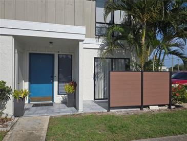 Inviting condo exterior with a bright blue door, neutral siding, privacy fence, and lush landscaping at 4001 Beneva Rd # 319, Sarasota, FL 34233