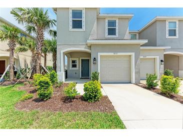 Charming two-story townhome with a one car garage, landscaping, and a welcoming front entrance at 5711 Archipelago St, Nokomis, FL 34275