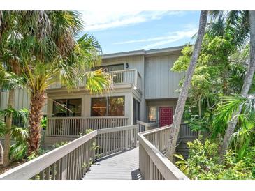 Charming two-story home featuring a balcony, a red door, and lush tropical landscaping at 1347 Landings Dr # 6, Sarasota, FL 34231