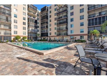 A swimming pool outside a condo building features a brick deck and patio seating at 2901 26Th W St # 204, Bradenton, FL 34205