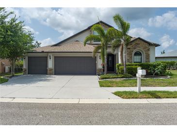 Charming single-Gathering home featuring a 3-car garage, stone accents, and tropical landscaping at 9236 Raes Creek Pl, Palmetto, FL 34221