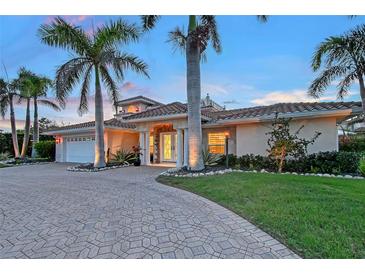 Stunning exterior with a paver driveway and lush landscaping with palm trees lining the entrance of this beautiful home at 571 Birdie Ln, Longboat Key, FL 34228