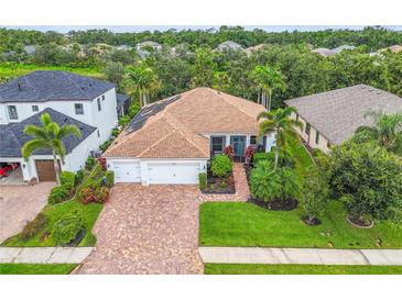 Well-maintained home featuring a brick driveway, two-car garage, and lush landscaping enhancing its curb appeal at 616 Dogwood Run, Bradenton, FL 34212