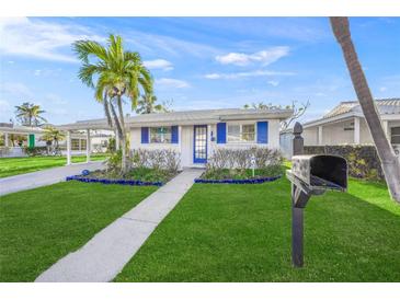 Charming single-story home with blue shutters, a palm tree, and a well-manicured lawn at 655 Spanish Way, Longboat Key, FL 34228