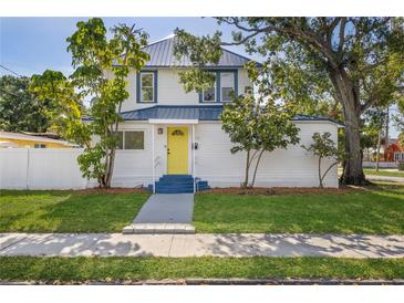 Charming home with a bright yellow door, complemented by lush landscaping and mature trees at 719 22Nd W St, Bradenton, FL 34205