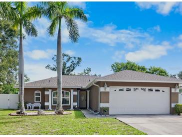 Charming home featuring lush lawn, mature palms, and a two-car garage at 2761 Feiffer Cir, Sarasota, FL 34235