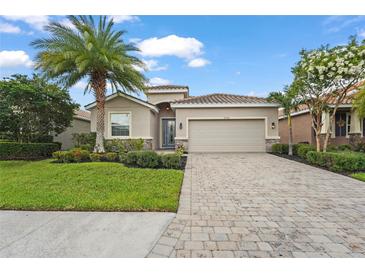 Charming single-story home featuring a lush green lawn, beautiful landscaping, and a paver driveway at 2920 Oriole Dr, Sarasota, FL 34243